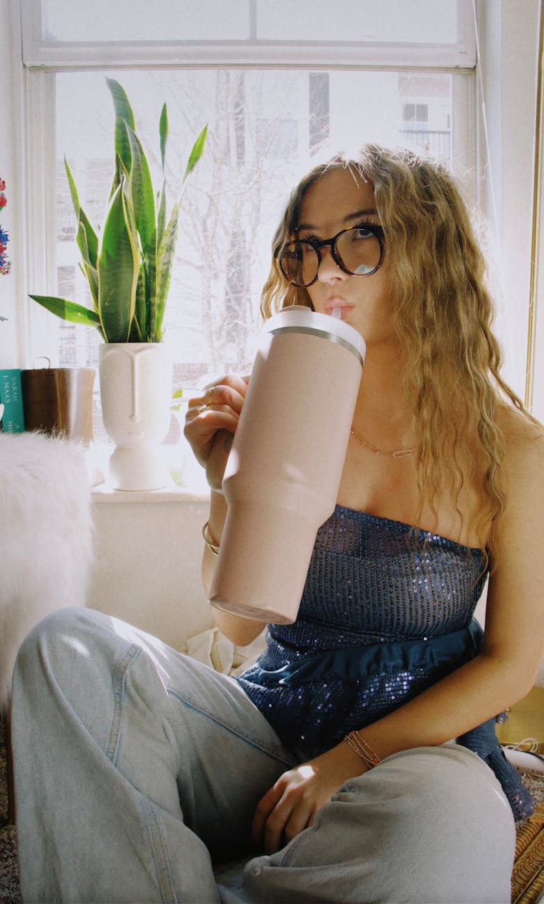 young woman drinking from a large stanley cup